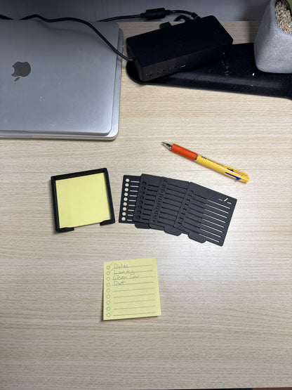 A collection of sticky notes, a pen, and a biodegradable plastic holder with stencils, displayed on a wooden surface.