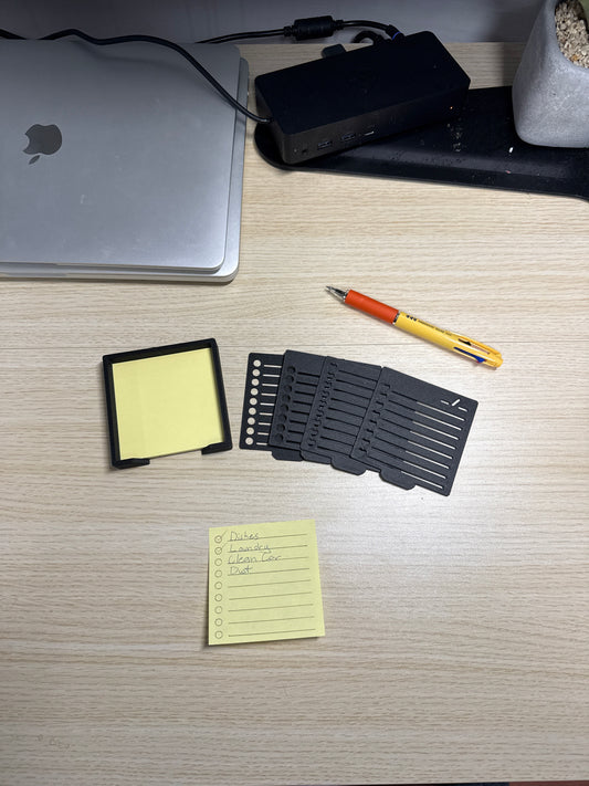 A collection of sticky notes, a pen, and a biodegradable plastic holder with stencils, displayed on a wooden surface.
