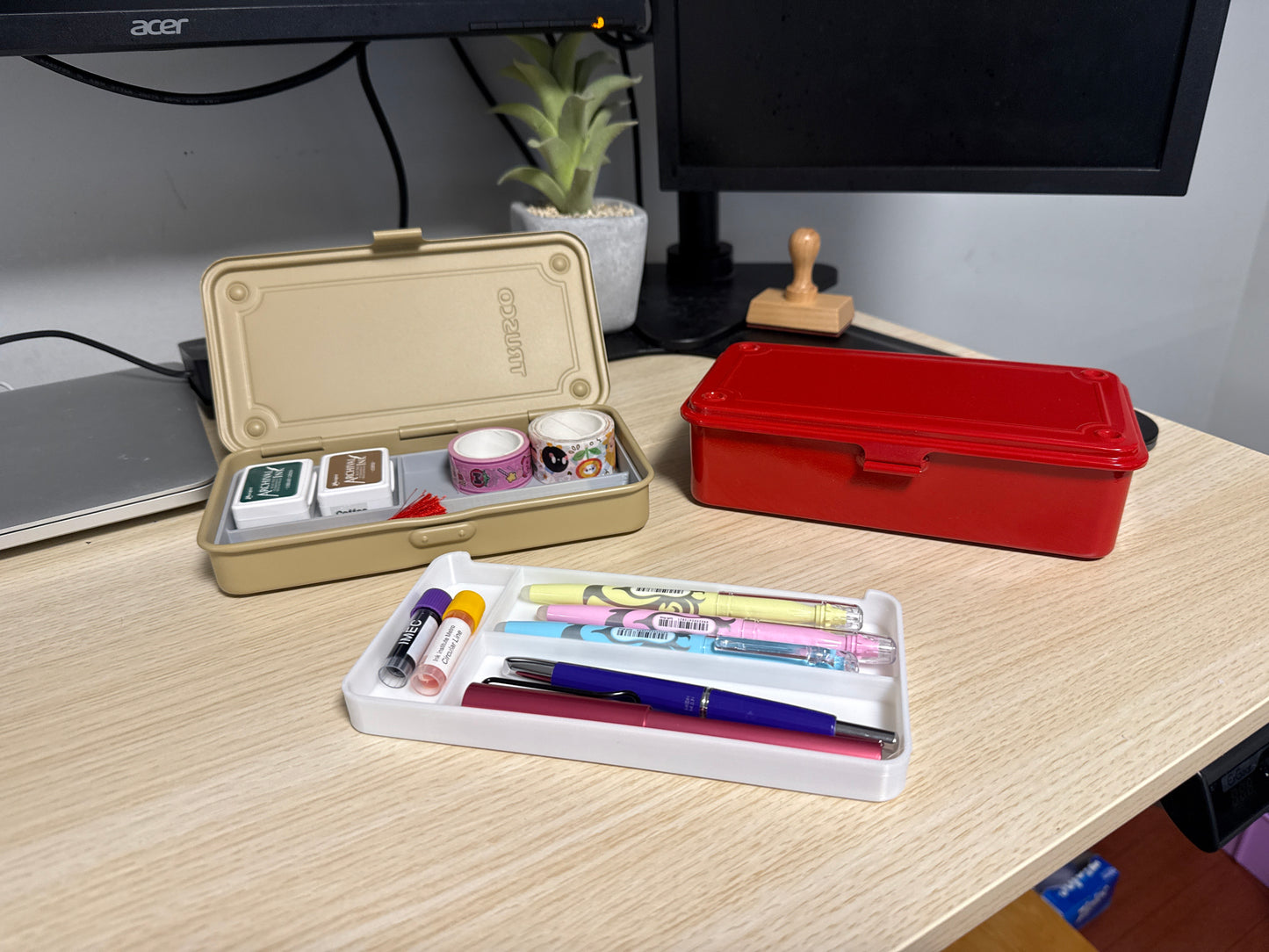 A set of 3D printed white inserts of various sizes displayed on a desk next to a beige toyo toolbox, and a red toyo toolbox. filled with washi tape and ink pads.