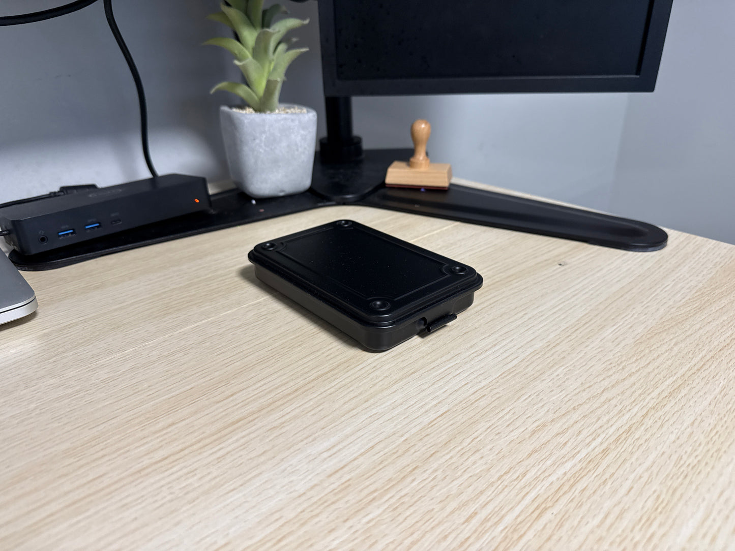 A Black Toyo T-152 stackable tool box placed on a wooden surface next to a computer monitor and a potted plant.