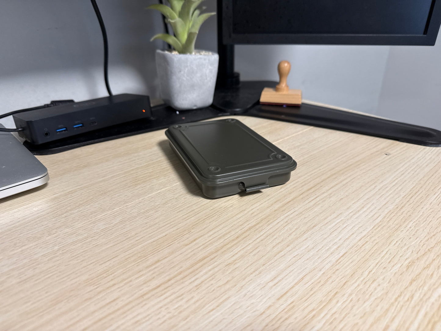 A green Toyo T-152 stackable tool box placed on a wooden surface, with a laptop, plant, and other items in the background.