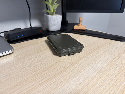 A green Toyo T-152 stackable tool box placed on a wooden surface, with a laptop, plant, and other items in the background.