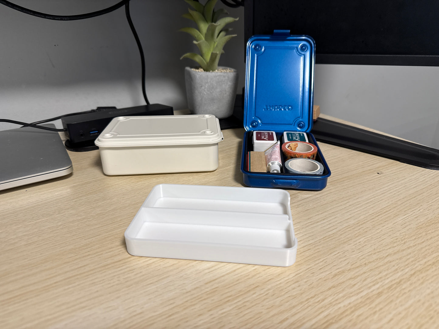 A set of 3D printed whiteinserts of various sizes displayed on a desk next to a blue trusco toolbox, and a silver trusco toolbox.